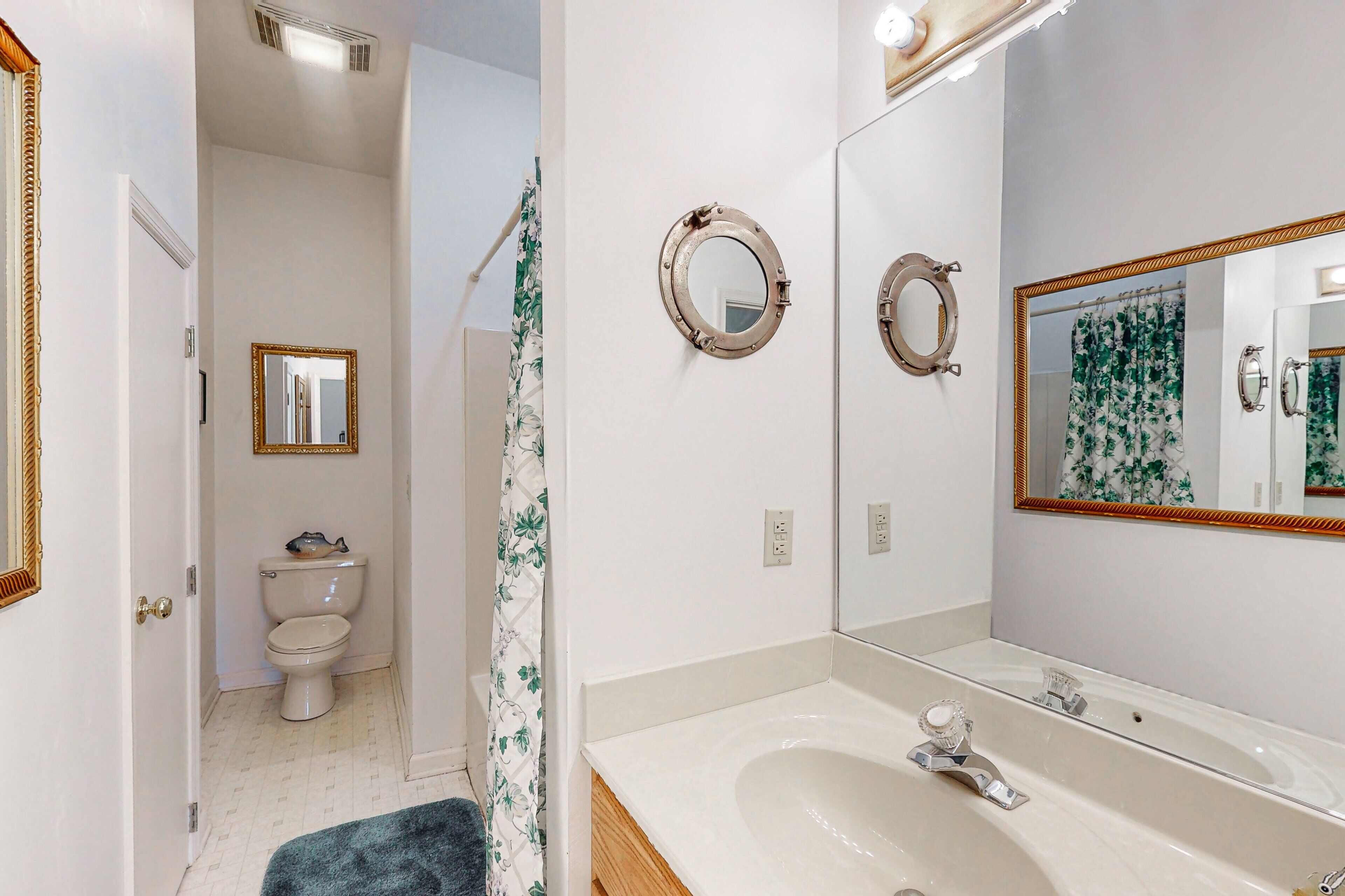 A bathroom with a toilet, a sink, and a mirror.