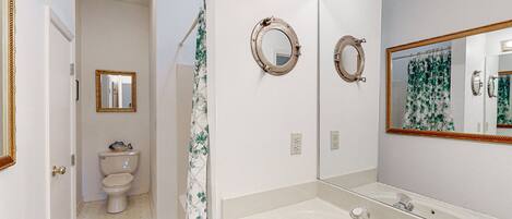 A bathroom with a toilet, a sink, and a mirror.