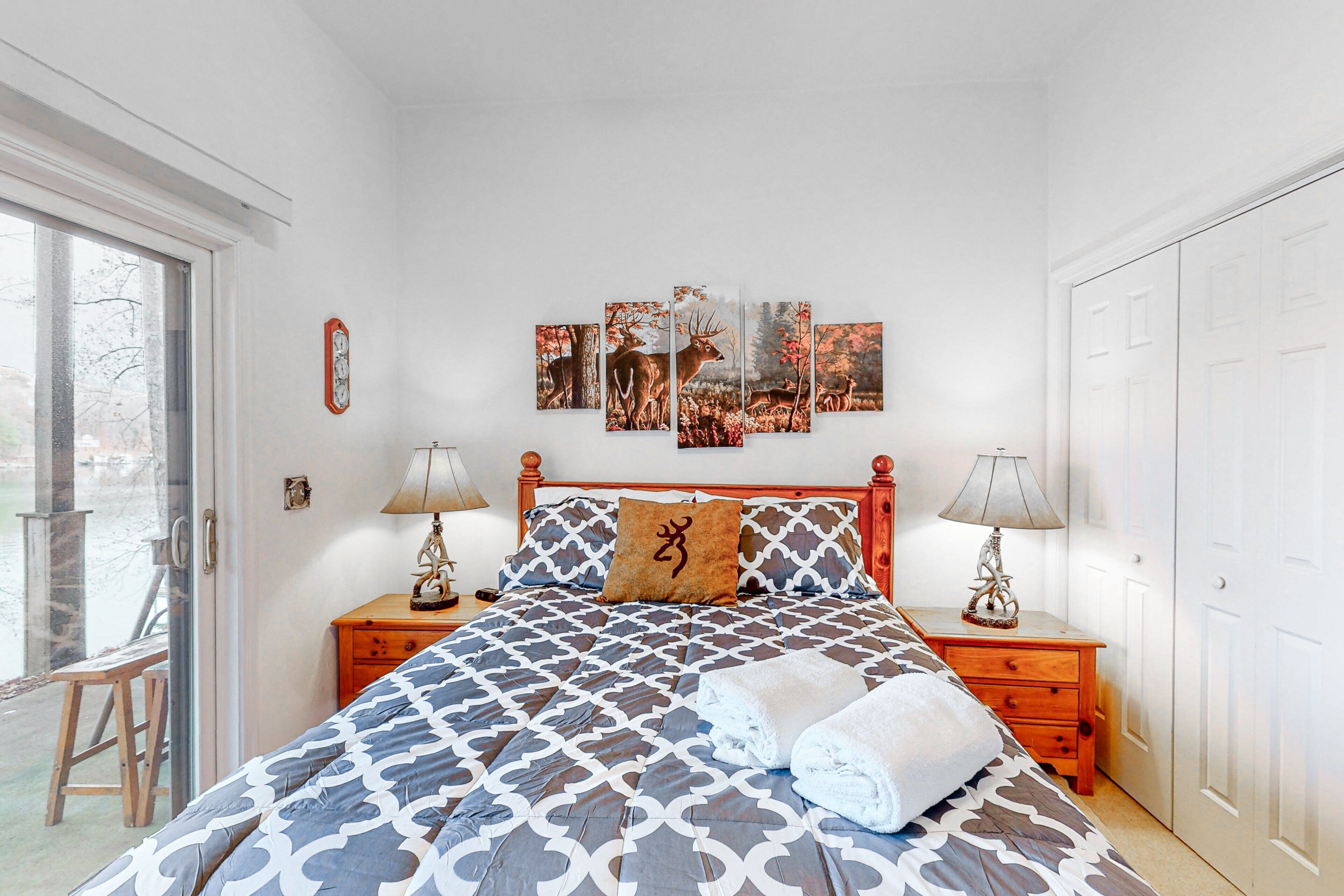 A bedroom with a bed, two nightstands, a window, and a door.