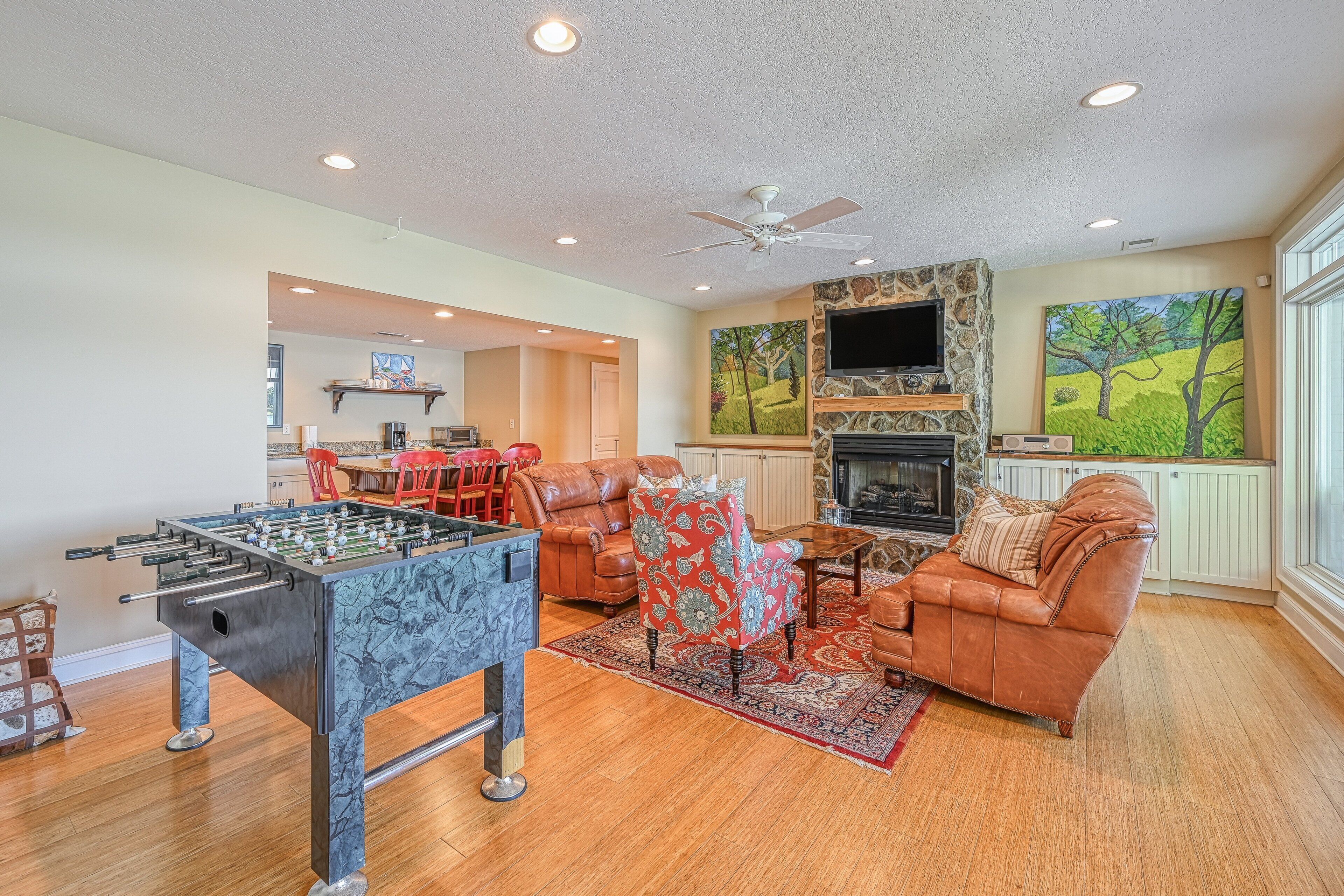 A living room with a foosball table, leather sofas, a fireplace, and a television.