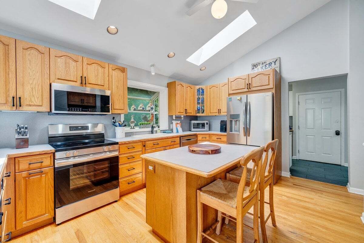 A modern kitchen with wooden cabinets, stainless steel appliances, and a central island.