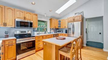 A modern kitchen with wooden cabinets, stainless steel appliances, and a central island.