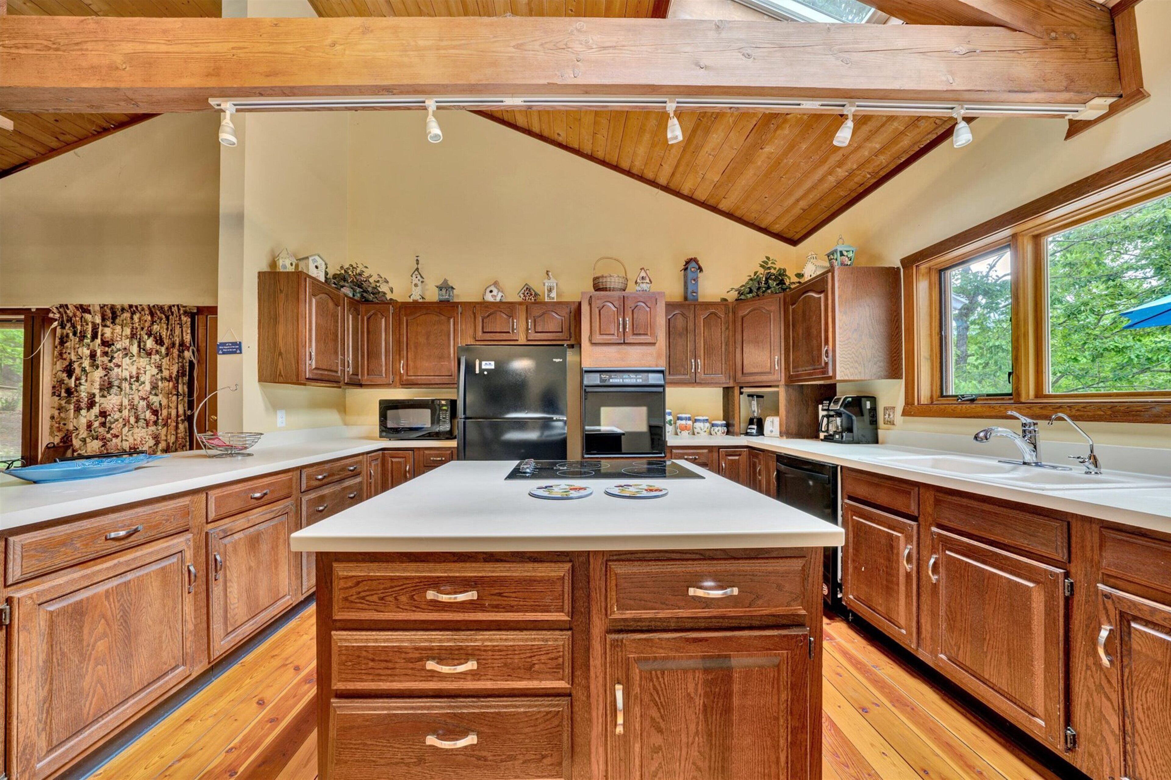 A kitchen with wooden cabinets, a central island, a refrigerator, and a microwave.