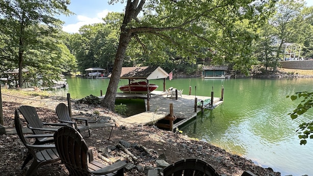 A lakeside setting with docked boats, a covered picnic area, and Adirondack chairs. - Humble Hideaway - Inviting Lakefront Home With Firepit, Balcony & W/D - Dog-friendly (Moneta)