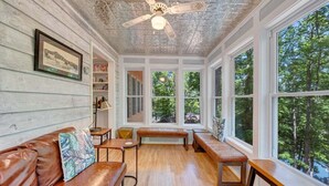 A room with a wooden ceiling, large windows, a brown leather sofa, and a bench. - Lakefront Tranquility - Lakefront Home With Views, Private hot Tub/dock, Deck, Free Wifi (Moneta)