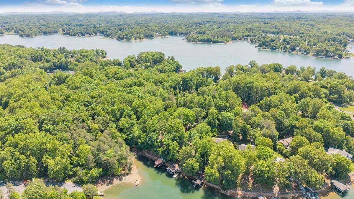 Une vue aérienne d’une zone boisée avec un lac, des bateaux et de petits bâtiments.