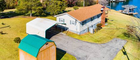 A residential property with a garage, a detached house, a dock, and a lake view.