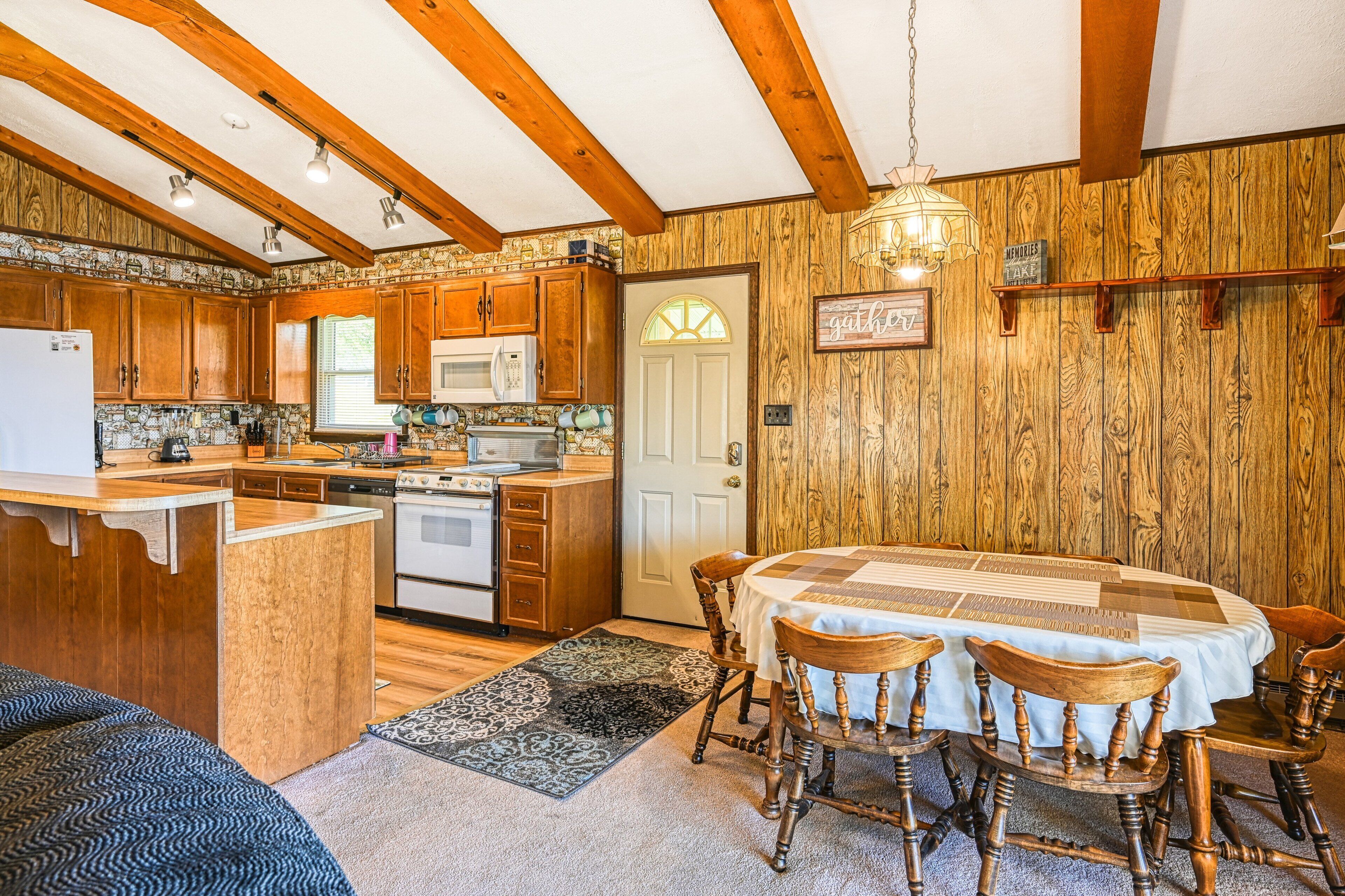 A kitchen with wooden cabinets, a central island, and a dining table with chairs.