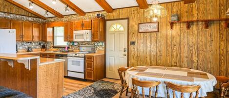 A kitchen with wooden cabinets, a central island, and a dining table with chairs.