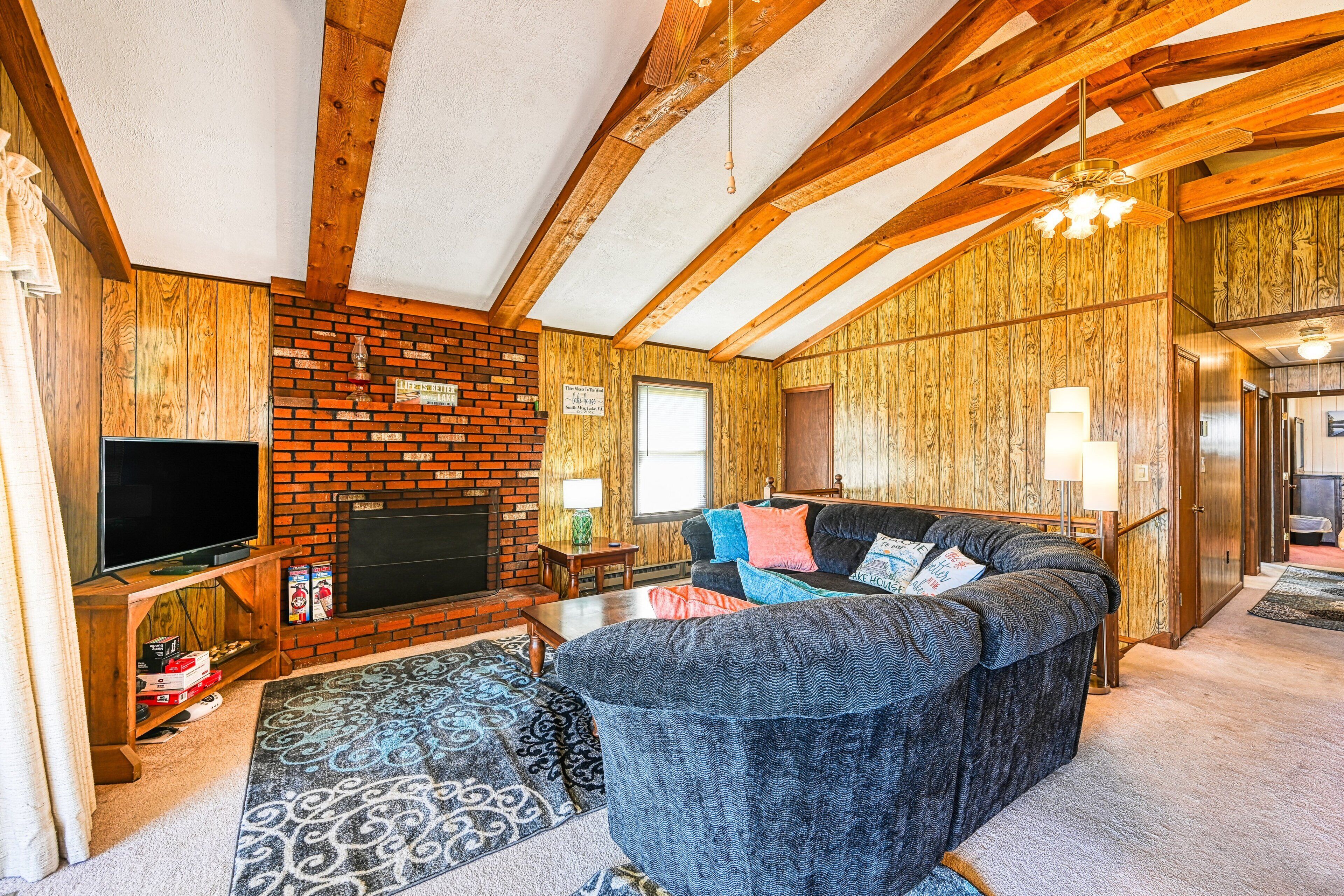 A living room with a fireplace, wooden ceiling beams, a television, and a sofa.