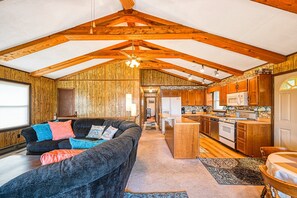 A spacious living area with a sofa, a kitchen with wooden cabinets, and a dining table. - Three Sheets to the Wind - Dog-friendly Lakefront Home With Dock, & Kayaks (Moneta)