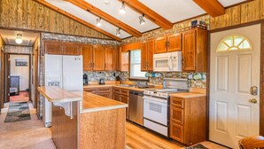 A kitchen with wooden cabinets, a central island, a microwave, an oven, and a refrigerator. - Three Sheets to the Wind - Dog-friendly Lakefront Home With Dock, & Kayaks (Moneta)