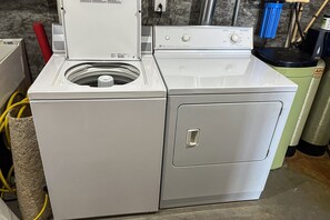 A front-loading washer and dryer unit with a control panel, a door handle, and a hose connected to the unit. - Lakedaze - Spacious Dog-friendly Lakefront House W/dock, hot tub & Putting Green (Moneta)