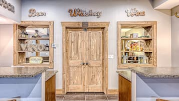 A bar area with wooden doors, shelves with liquor bottles, and a sign reading 'Deep Eddy Lemon.'