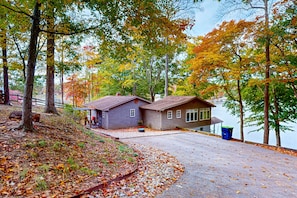 A cabin with a dock, surrounded by trees and a lake.