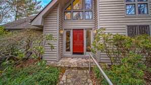 A house with a red door, stone steps, and a small garden. - Our Point of View - Lakefront Home With hot Tub, Pool Table, Dock - Dog-friendly (Huddleston)