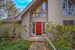 A house with a red door, stone steps, and a small garden. - Our Point of View - Lakefront Home With hot Tub, Pool Table, Dock - Dog-friendly (Huddleston)