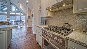 A kitchen with a large stove, granite countertops, and a dining area with a view. - Our Point of View - Lakefront Home With hot Tub, Pool Table, Dock - Dog-friendly (Huddleston)