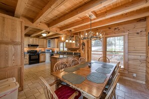 L’intérieur d’un chalet en bois comprend une table à manger, des chaises, un coin cuisine et de grandes fenêtres.