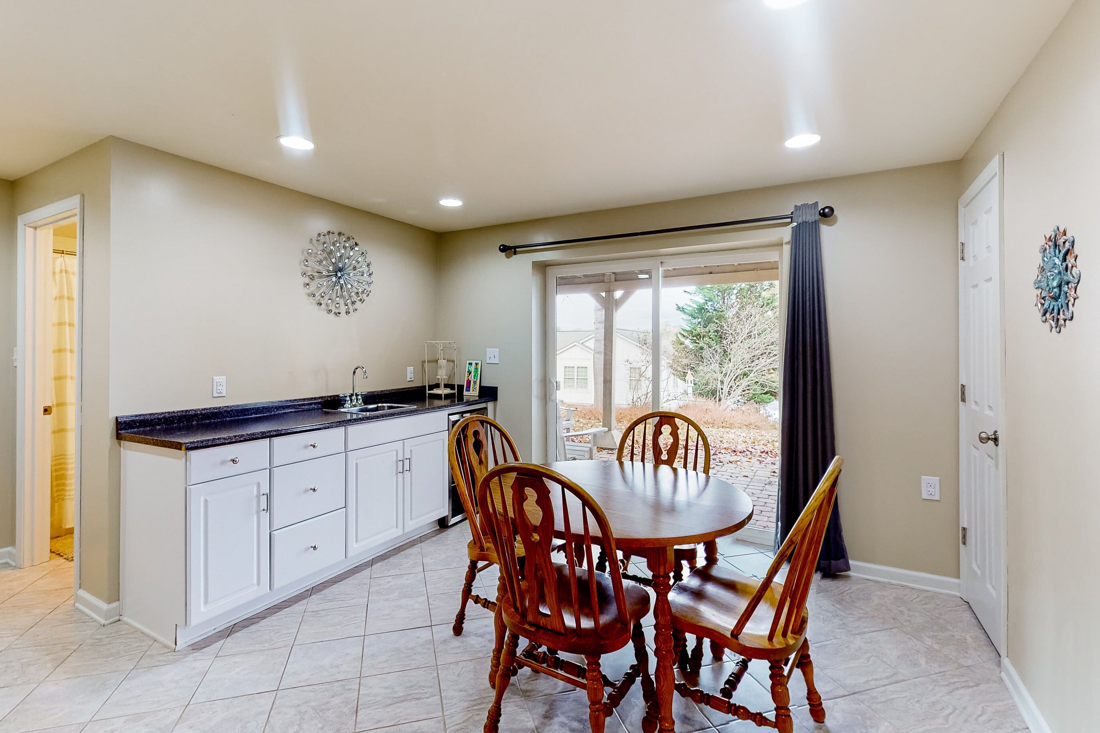 A kitchen with a dining table and chairs, a window with curtains, and a door.