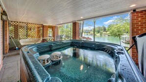 Ein Whirlpool mit Seeblick, umgeben von Ziegelmauern und großen Fenstern.