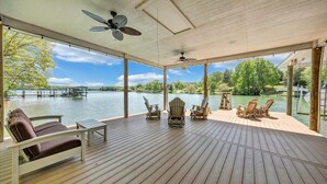 Eine Terrasse im Freien mit Holzboden, Deckenventilatoren und Adirondack-Stühlen.