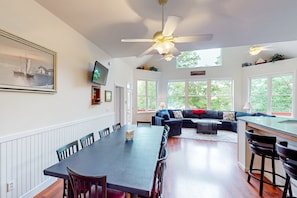 A spacious living area with a dining table, a sofa, and a kitchen area with a bar. - Still Waters - Lakefront Luxury Home With Views, Dock, Home Theater & Game Room (Goodview)