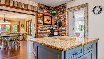 A kitchen with a granite countertop, wooden cabinets, and a brick accent wall.