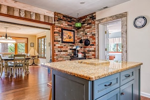 Una cocina con encimera de granito, armarios de madera y una pared decorativa de ladrillo.