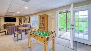 Een kamer met een tafelvoetbalspel, een bank, een televisie en een kast.