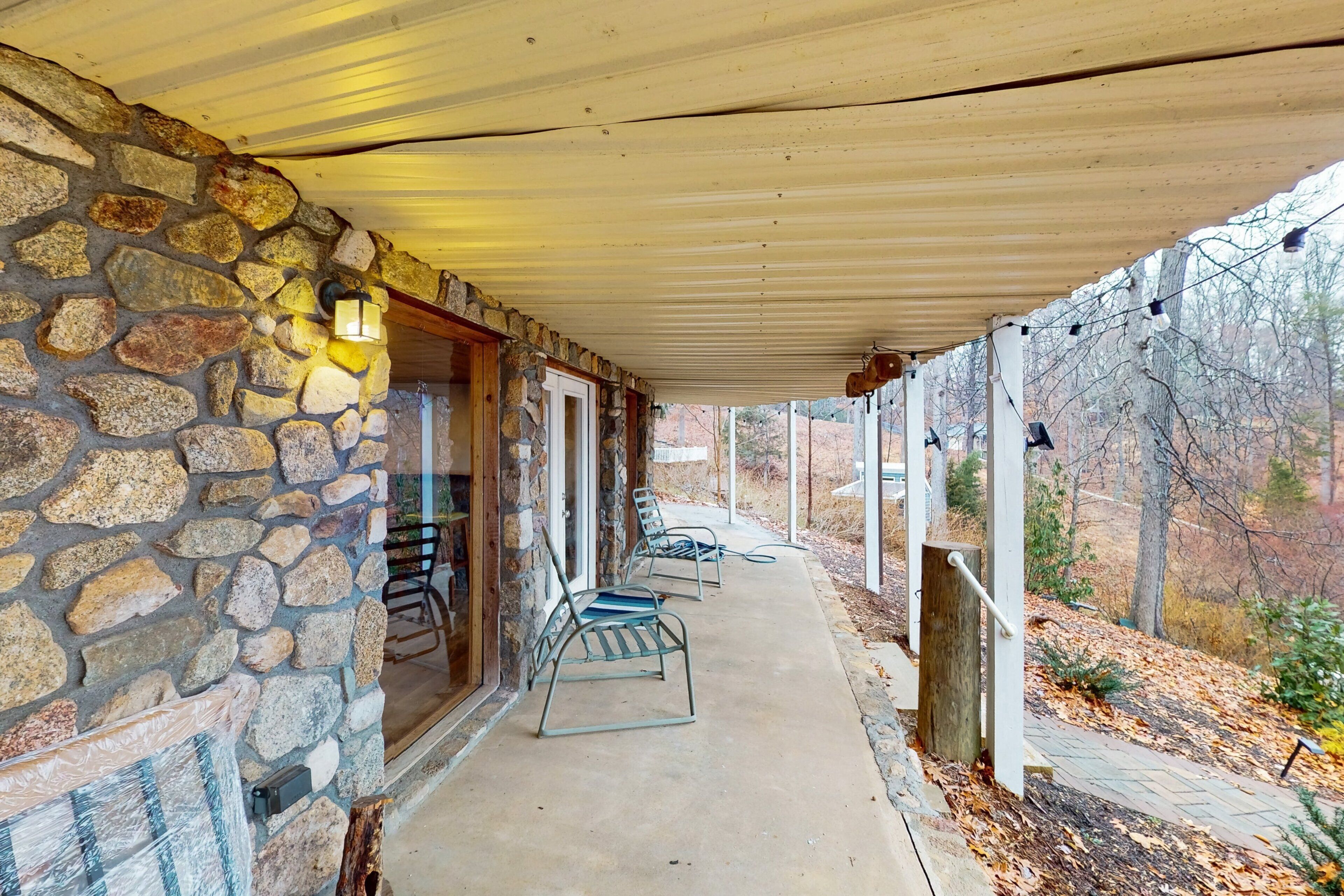 A stone building with a covered porch, outdoor seating, and a view of the surrounding landscape.