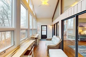 Ein modernes Interieur mit großen Fenstern, einer hölzernen Bank, einem Sofa und einem Deckenventilator.