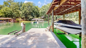 Un molo di legno si protende in un'area d'acqua verde, con una barca ormeggiata a destra.