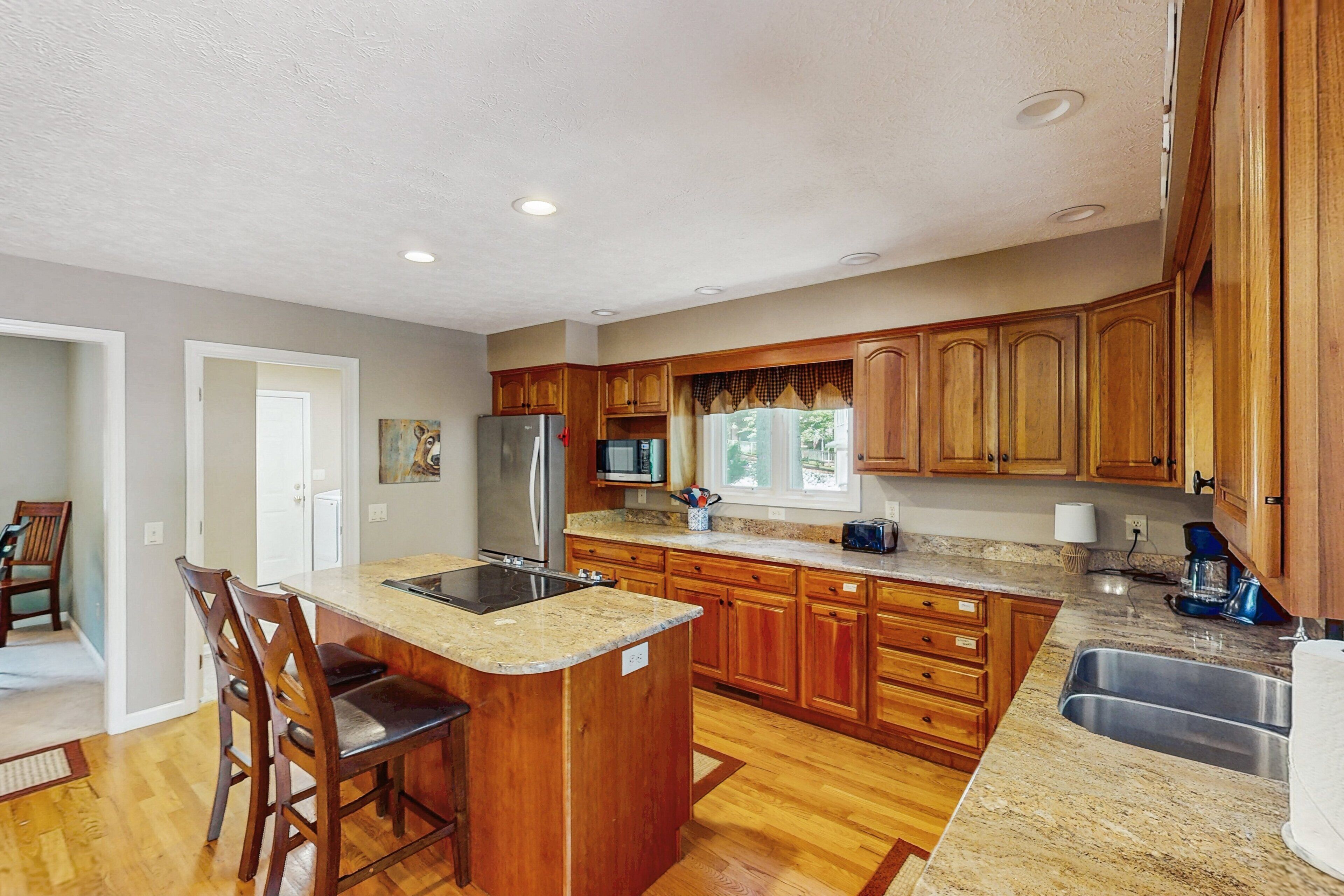 A kitchen with wooden cabinets, a granite countertop, a stainless steel sink, and a built-in oven.