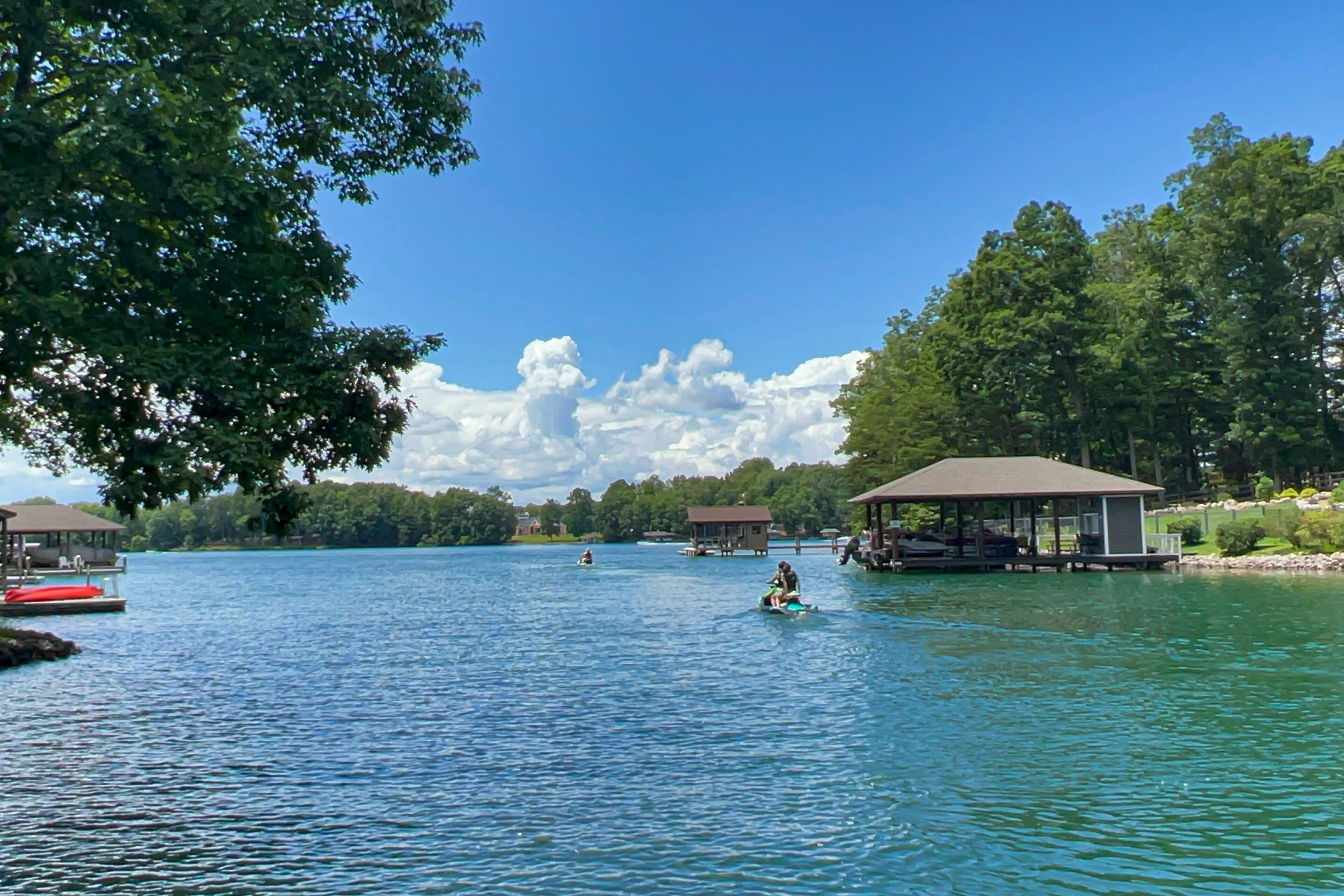 Une vue sur le lac avec des bateaux amarrés, un espace de repos abrité et un pavillon.