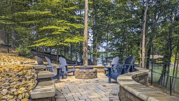 Una veranda esterna con poltrone Adirondack, un braciere in pietra e un muro in pietra.