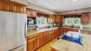 Cucina con mobili in legno, frigorifero in acciaio inossidabile, microonde, piano cottura e lavastoviglie.