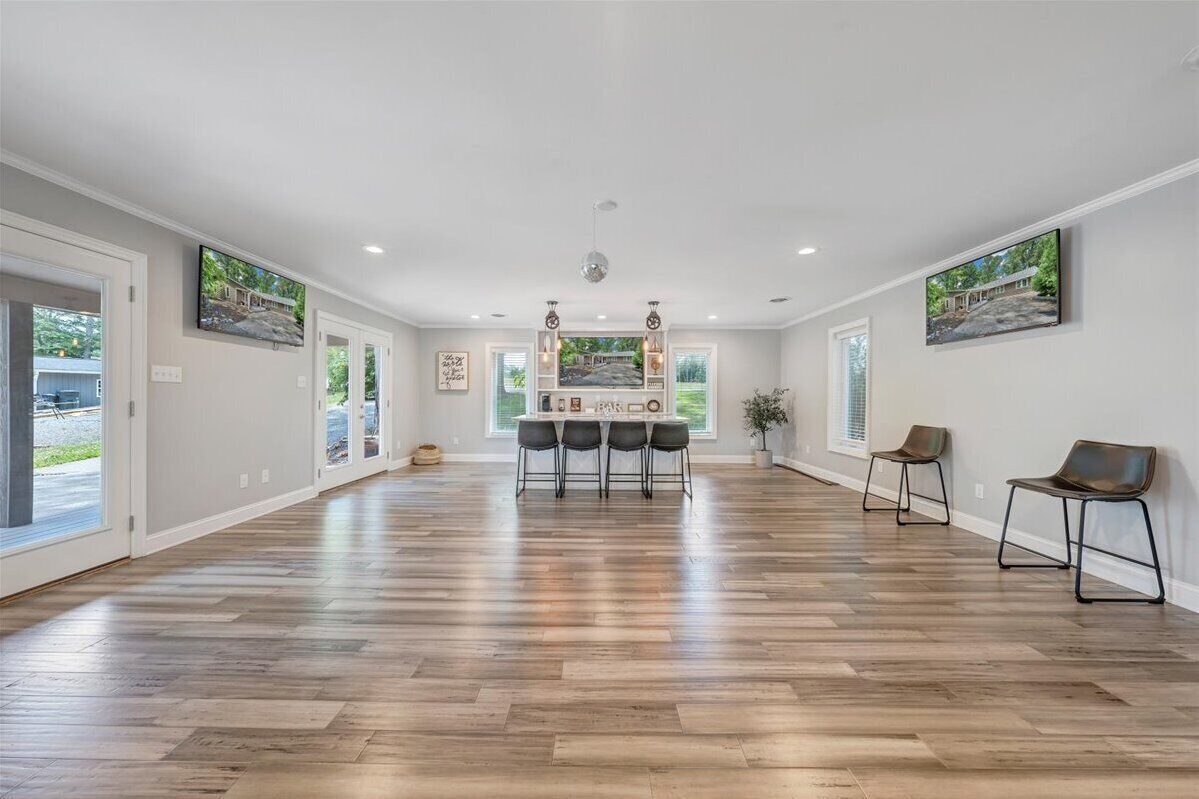 A spacious room with a long wooden floor, a central dining table with chairs, and two side chairs.