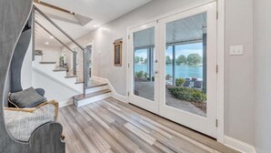 Ein modernes Interieur mit Treppe, einer Sitzecke und Blick auf ein Gewässer durch Glastüren.