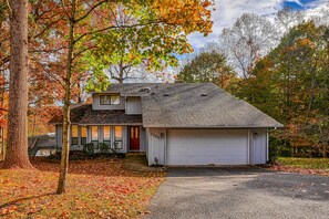 Ein zweistöckiges Haus mit Garage, umgeben von Bäumen mit Herbstlaub.