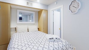 A hotel room with a bed, a mirror, a clock, and a door. - Sunset Landing - Waterfront Condo With Lake-view Deck, Tennis Court & Pool (Moneta)