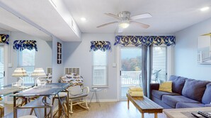 A dining area with a glass table, chairs, and a ceiling fan. - Sunset Landing - Waterfront Condo With Lake-view Deck, Tennis Court & Pool (Moneta)