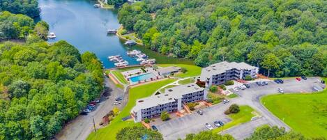 An aerial view of a hotel with a swimming pool, parking lot, and docked boats.