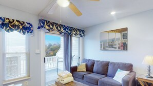 A living room with a sofa, a coffee table, a ceiling fan, and a view of the outdoors. - Sunset Landing - Waterfront Condo With Lake-view Deck, Tennis Court & Pool (Moneta)
