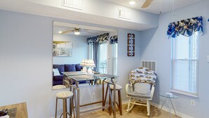A dining area with a glass table, wooden chairs, a ceiling fan, and a view of a living room through a large mirror. - Sunset Landing - Waterfront Condo With Lake-view Deck, Tennis Court & Pool (Moneta)