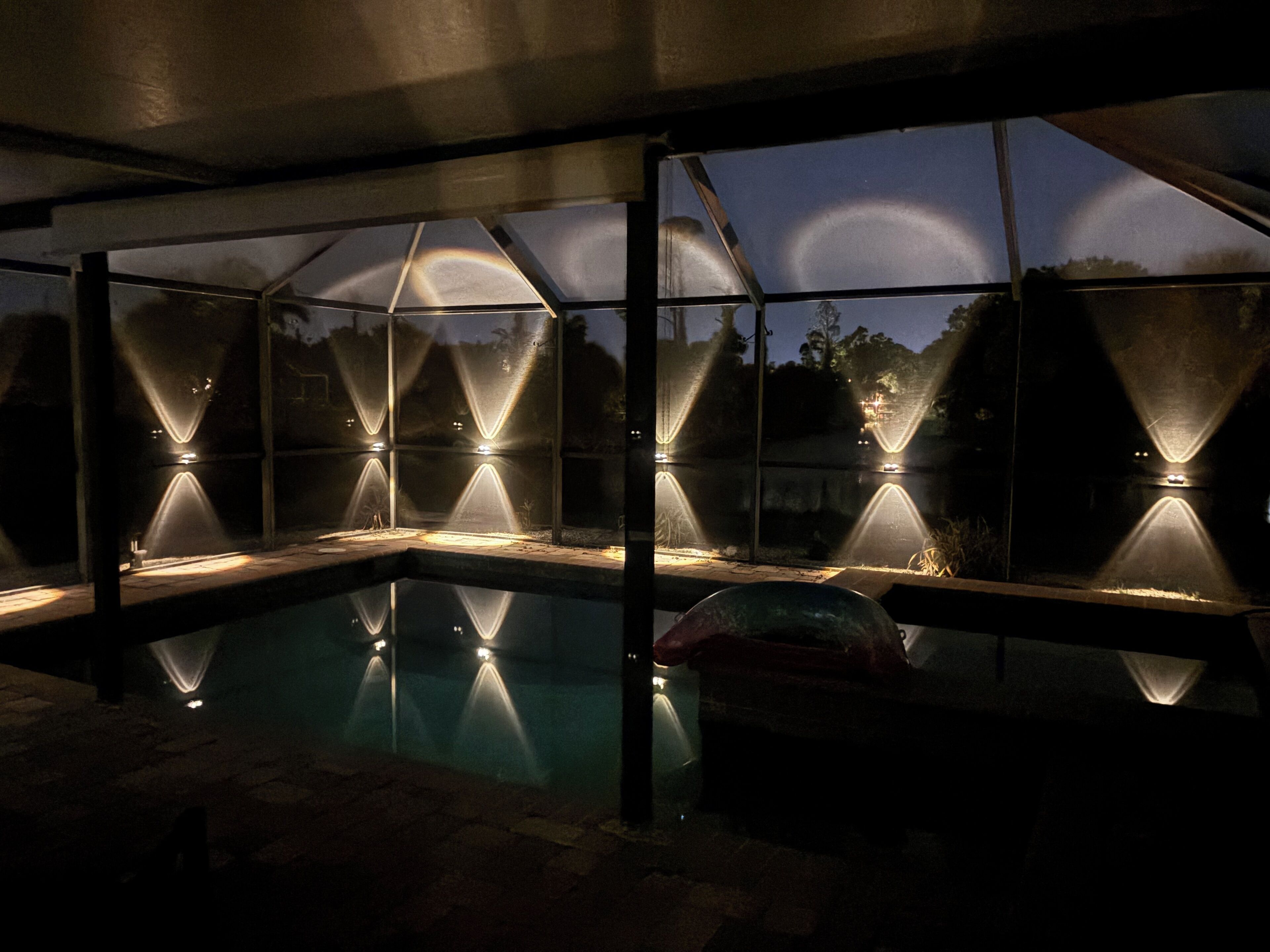 A pool area with a glass enclosure and multiple light fixtures.