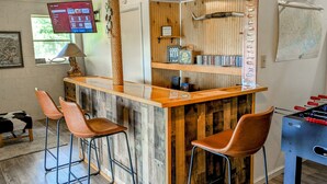 Een bar met krukken, een tafelvoetbalspel en een televisiescherm waarop een menukaart wordt getoond.