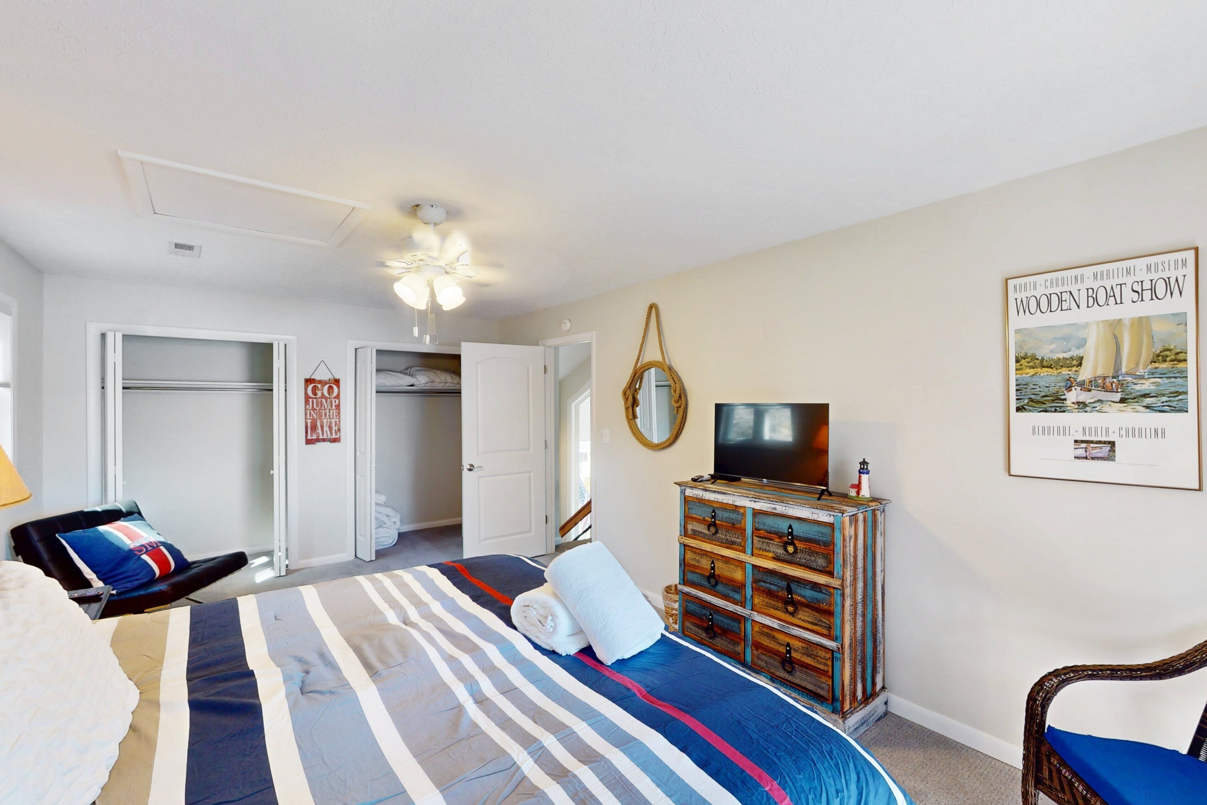 A bedroom with a bed, a dresser, a television, and a poster on the wall.