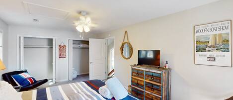 A bedroom with a bed, a dresser, a television, and a poster on the wall.