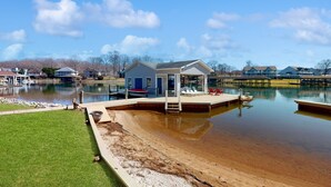 A lakeside property with a dock, a small house, and a swimming area. - Sail Away - Waterfront Home With Private Beach on the Lake, hot Tub, & Dock (Huddleston)